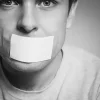 Person with tape over their mouth, symbolising loss of voice and originality in content plagiarism